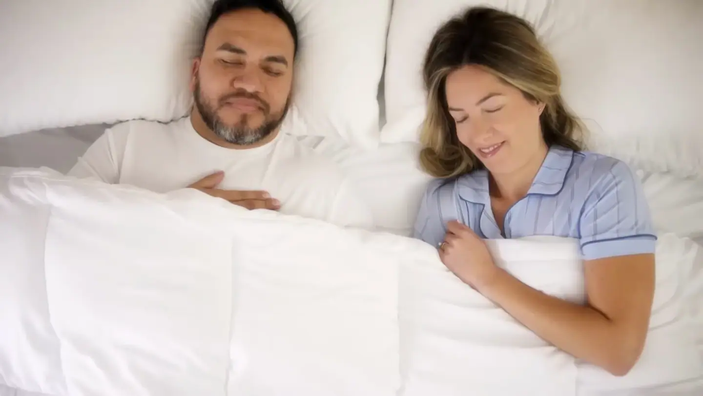 A couple asleep under a white duvet, from Mancini's Sleepworld's own advertising