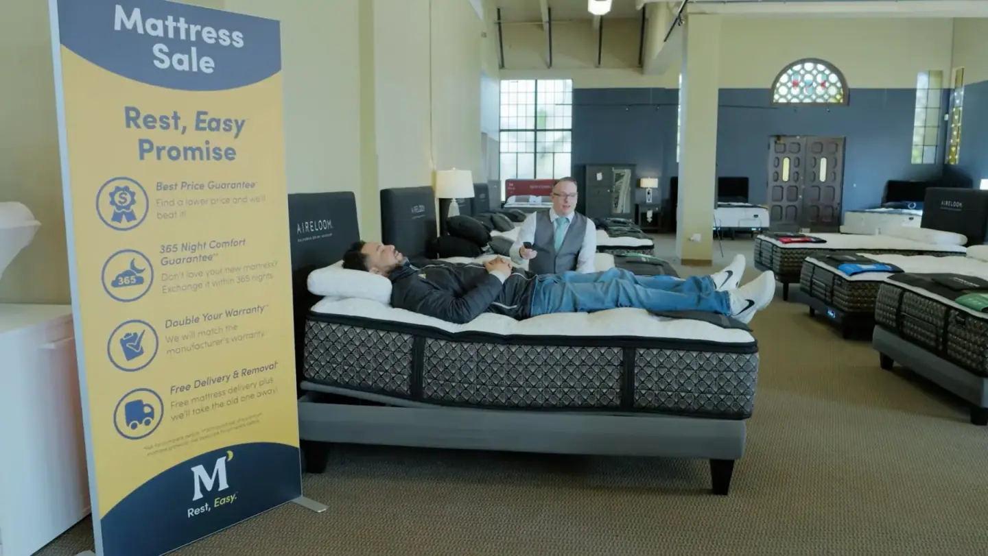 A Mancini's sleep specialist with a customer trying a mattress in the showroom