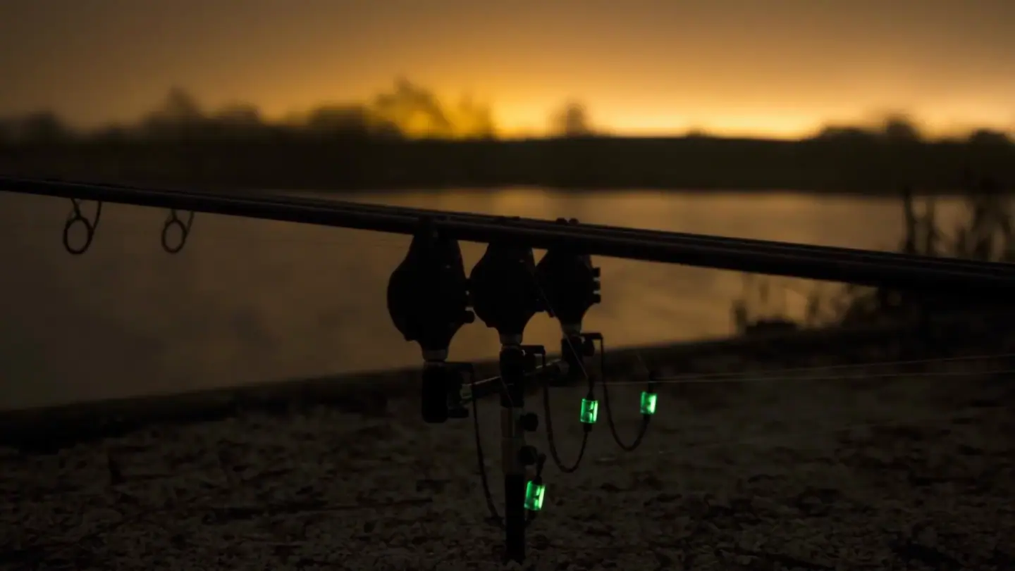 Carp rods and bite alarms on a lakeside at dusk, from KUMU's film Adrift