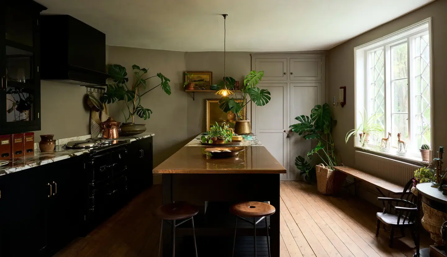 A deVOL kitchen with dark cabinetry, a long wooden island and a brass pendant light